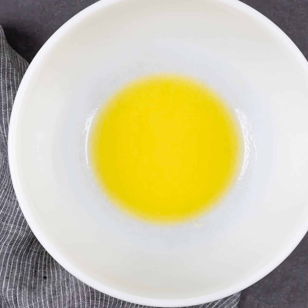 Captioned process step of melted butter in a white bowl.