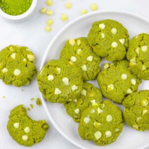White plate of white chocolate matcha cookies with a bite out of one cookie.