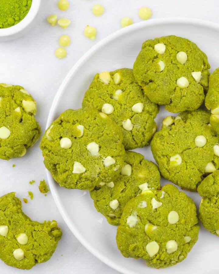 White plate of white chocolate matcha cookies with a bite out of one cookie.