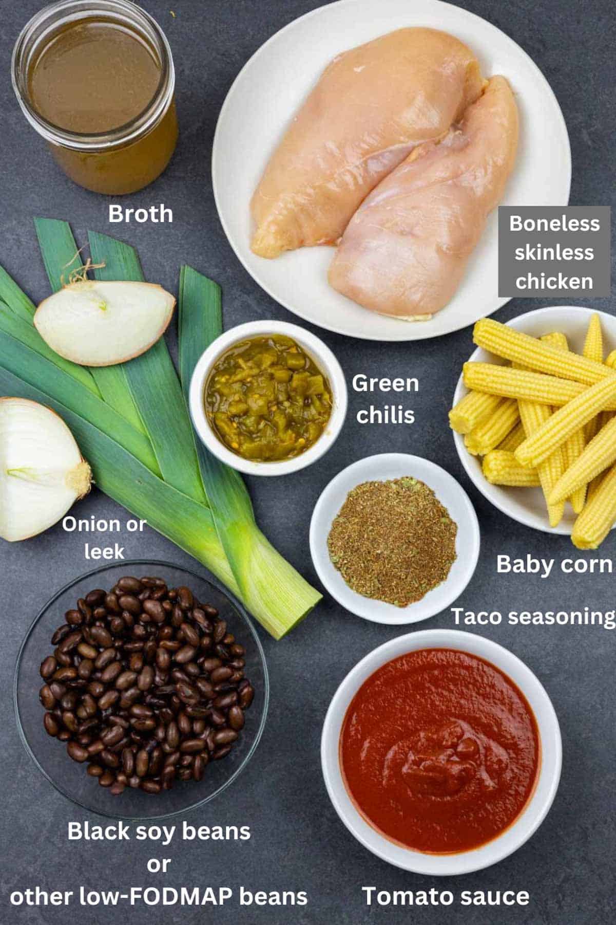 Ingredients for chicken taco soup on a grey board with white text labels.