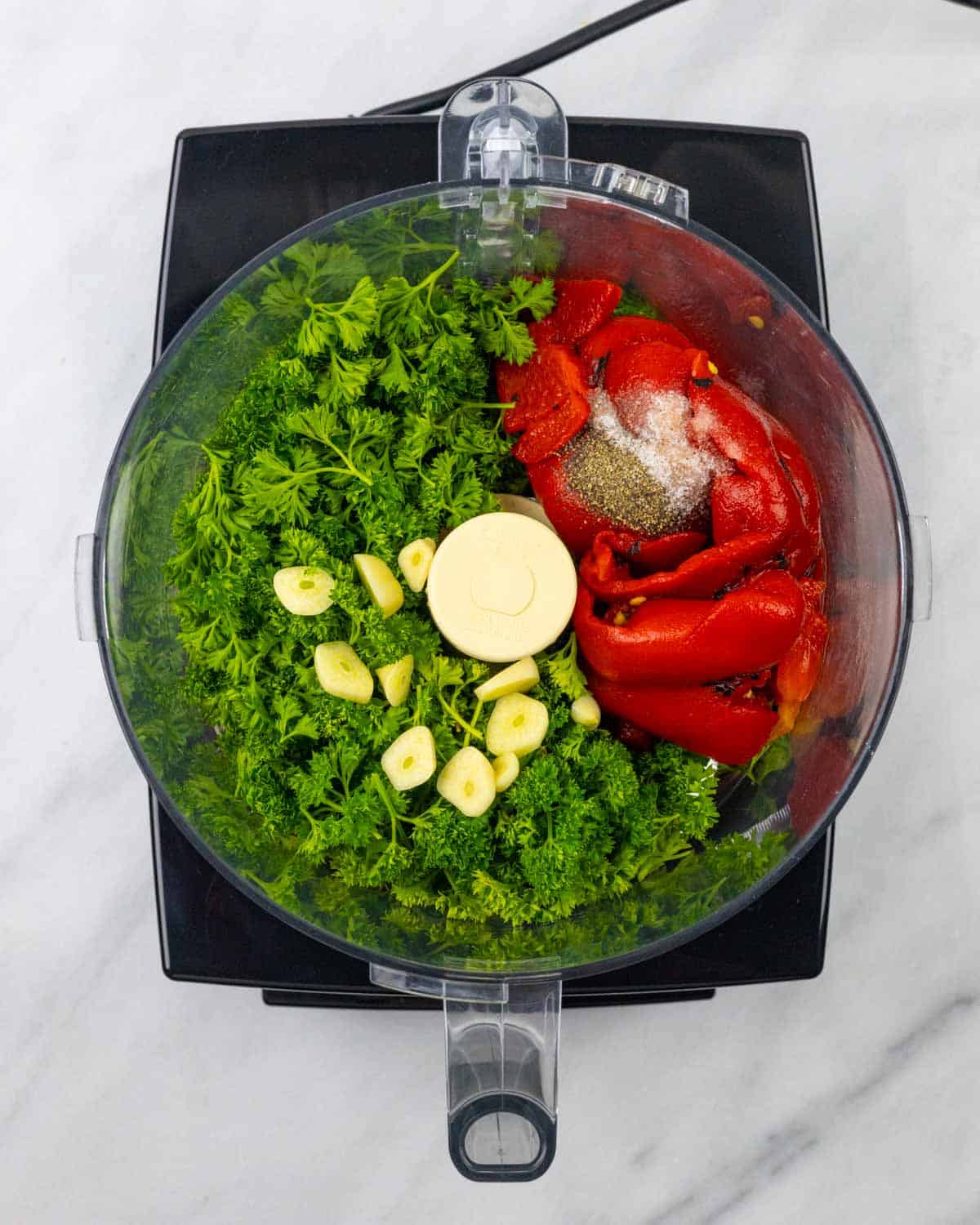 Looking down into food processor bowl at chimichurri ingredients prior to blending.