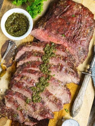Smoked flank steak sliced and drizzled with green chimichurri sauce.