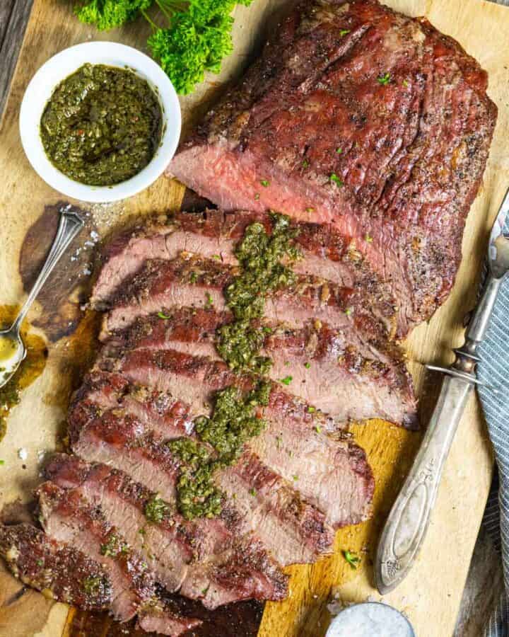 Smoked flank steak sliced and drizzled with green chimichurri sauce.
