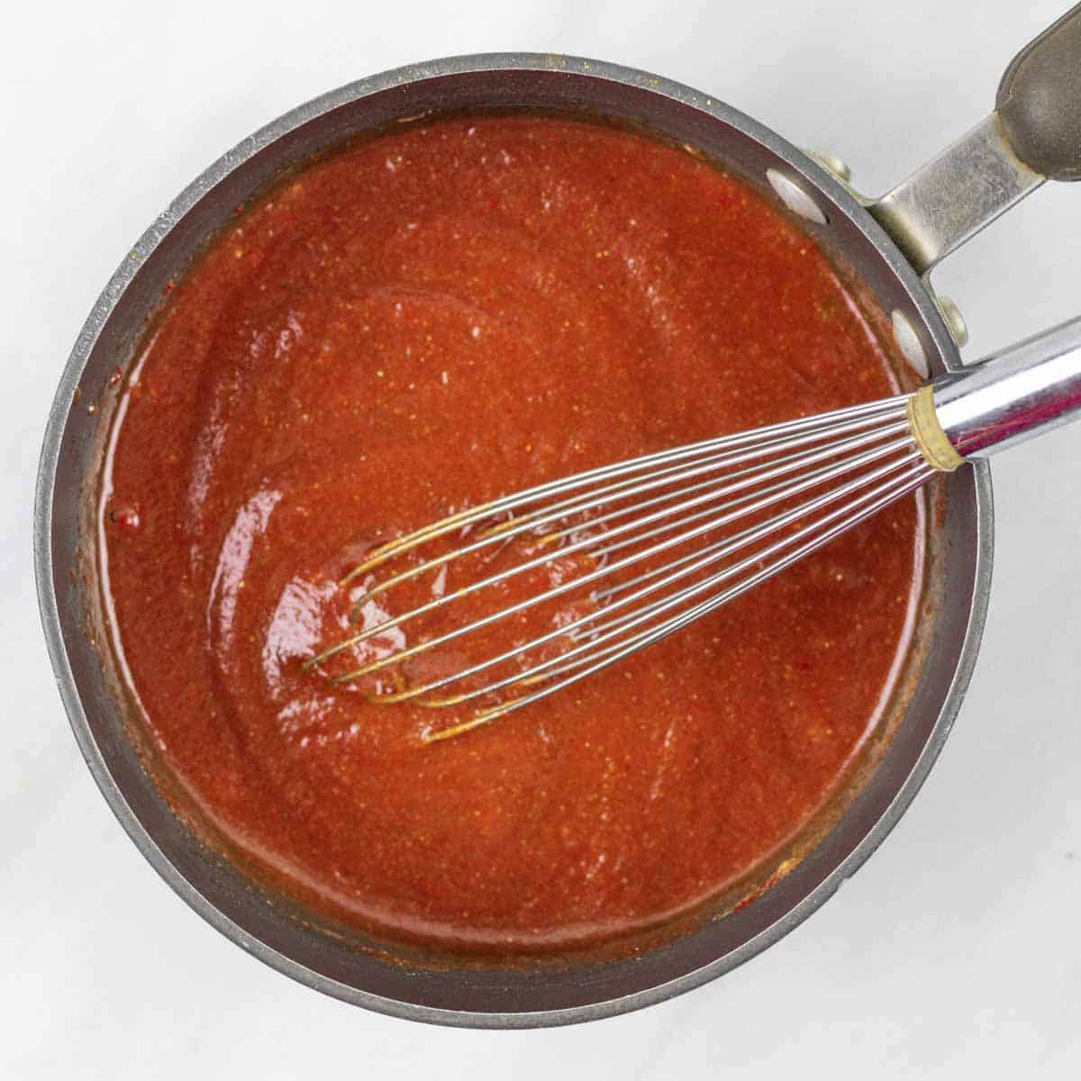 Whisked together bbq sauce ingredients in a pot with a whisk before simmering.