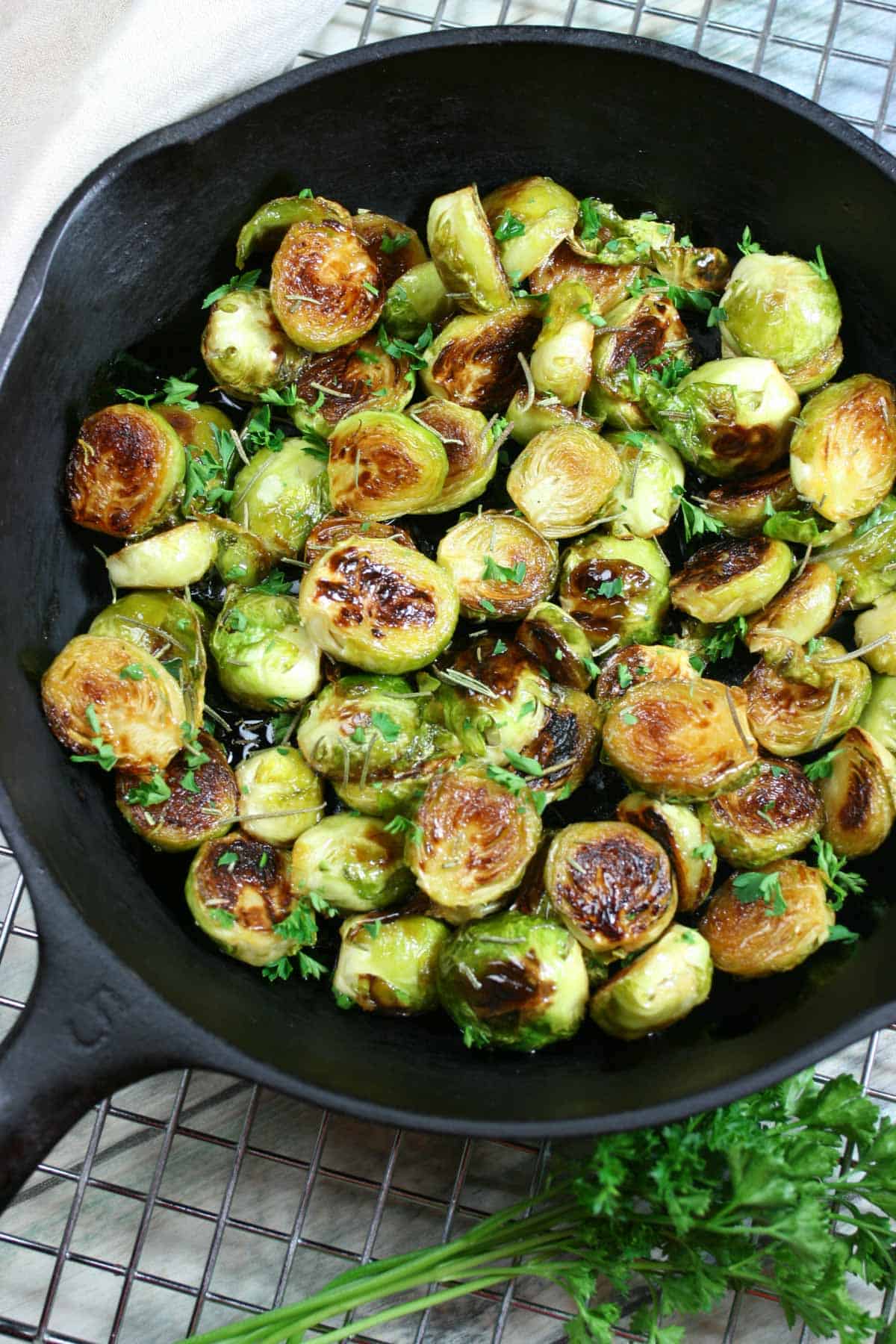 Brussels with maple and rosemary garnished with parsley in a cast iron skillet.