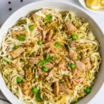 Bowl of pasta with tuna and pesto decorated with basil leaves.