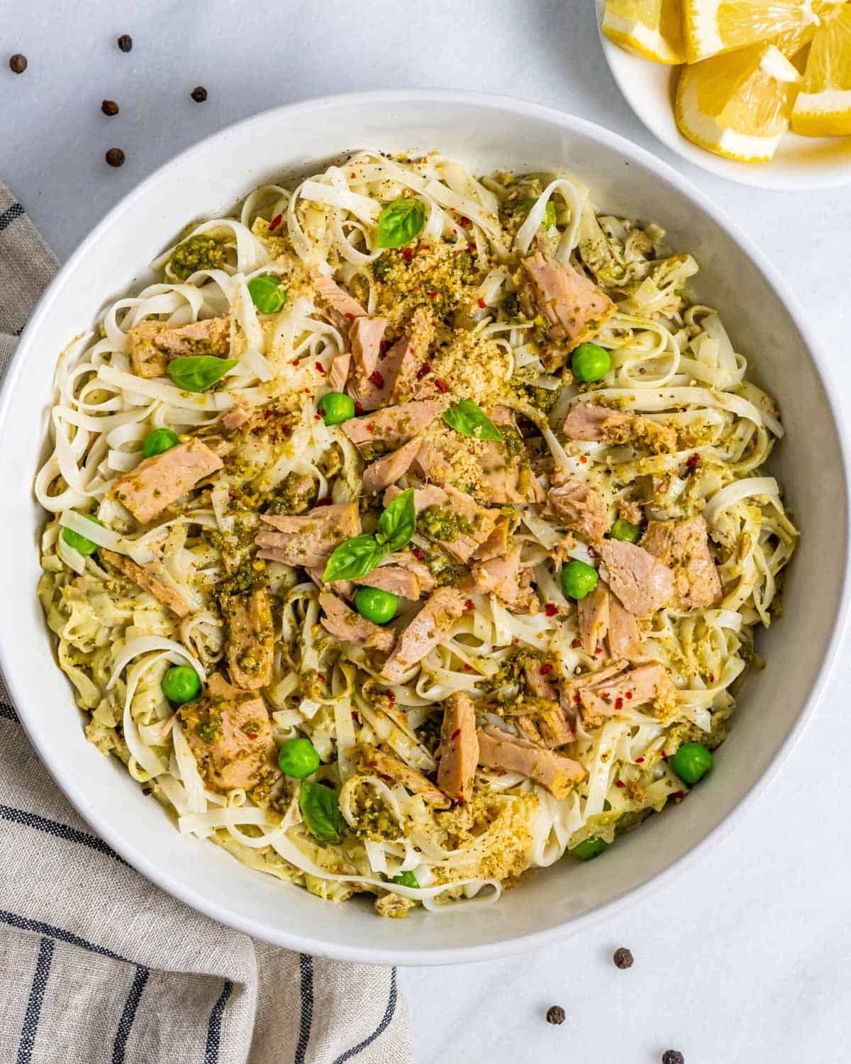 Bowl of pasta with tuna and pesto decorated with basil leaves.