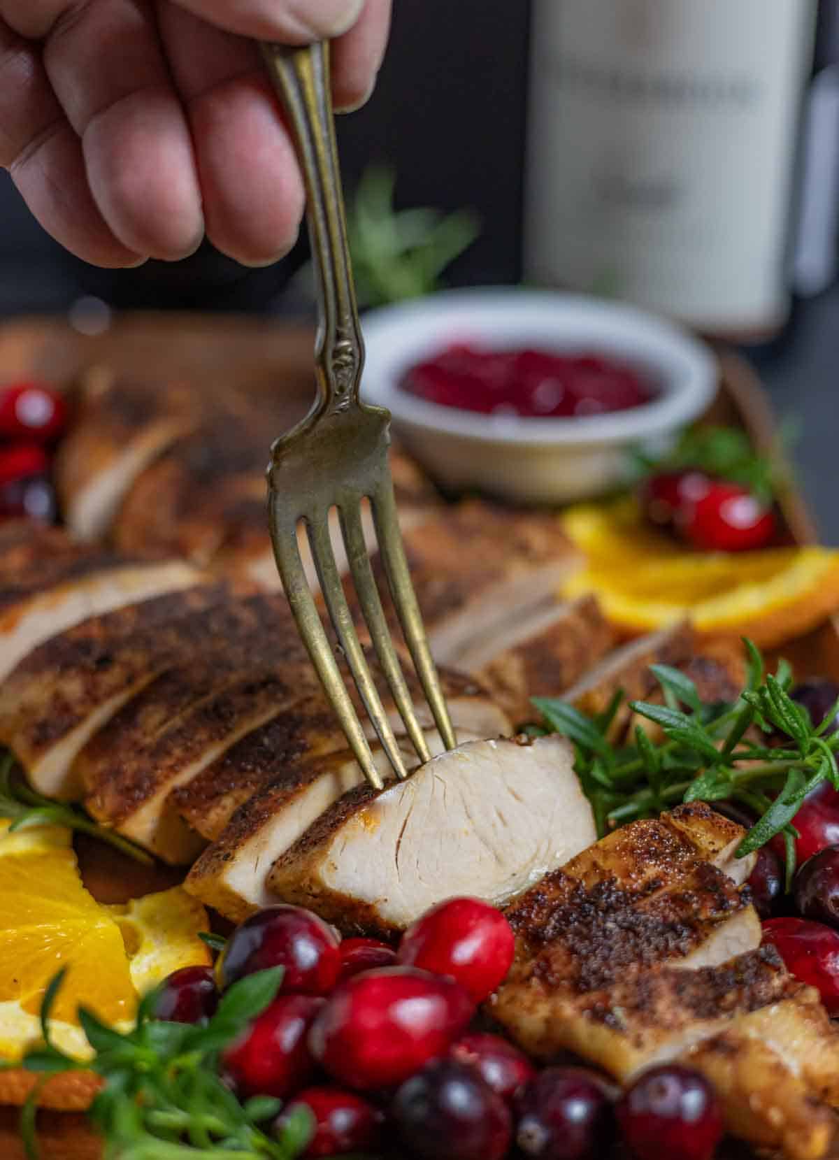 Sliced turkey tenderloin with a fork selecting one slice.