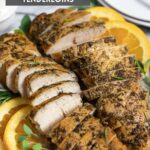 Slow cooker seasoned turkey breast tenders sliced on a plate with herbs and orange slices.