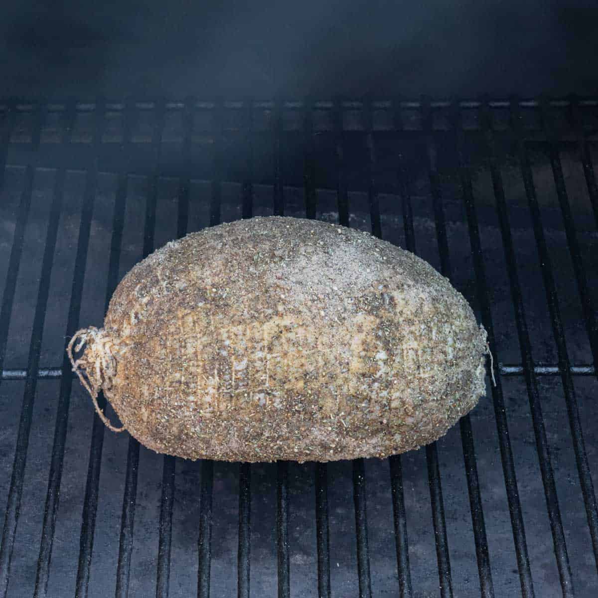 Seasoned breast placed on the smoker grill grates.