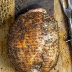 Whole boneless turkey breast after smoking on a board ready to slice.