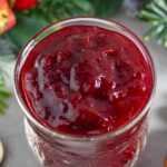 Bright red cranberry jam in an open jar.