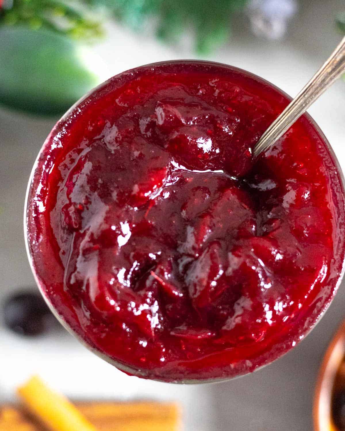 Jar of cranberry jam with a spoon in it.