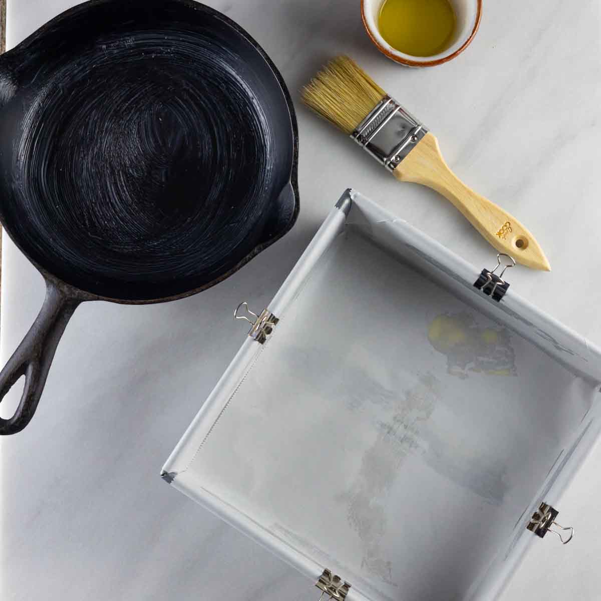 Oiled cast iron skillet, and square baking pan lined with parchment.