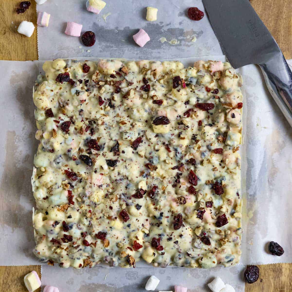 Entire block of rocky road on parchment on a board ready to slice.