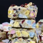 Stack of rocky road squares showing colorful marshmallows and toppings.