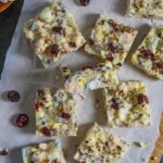 Squares of rocky road topped with dried cranberries on parchment.