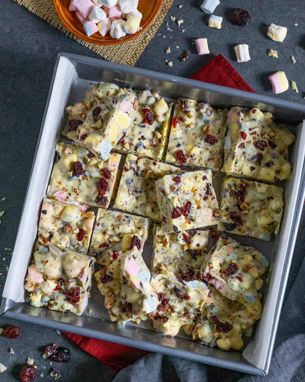 Square pan of white chocolate rocky road cut into squares with some tilted upward.