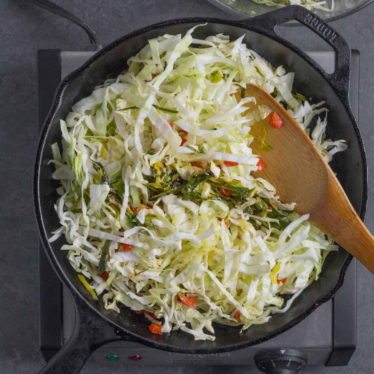 Remaining cabbage in skillet with vegetables and spices on simmer.