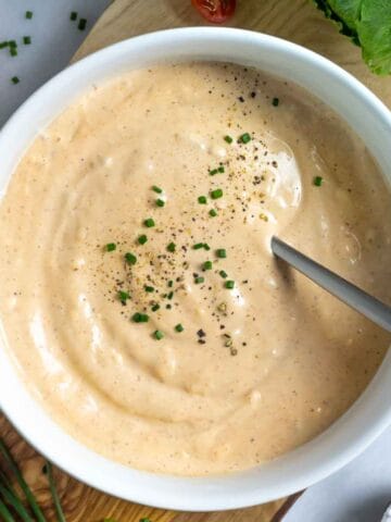 Gluten-free Thousand Island Dressing in a white bowl sprinkled with chopped chives and pepper.