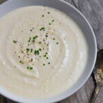 Bowl of horseradish sauce sprinkled with chives and black pepper.