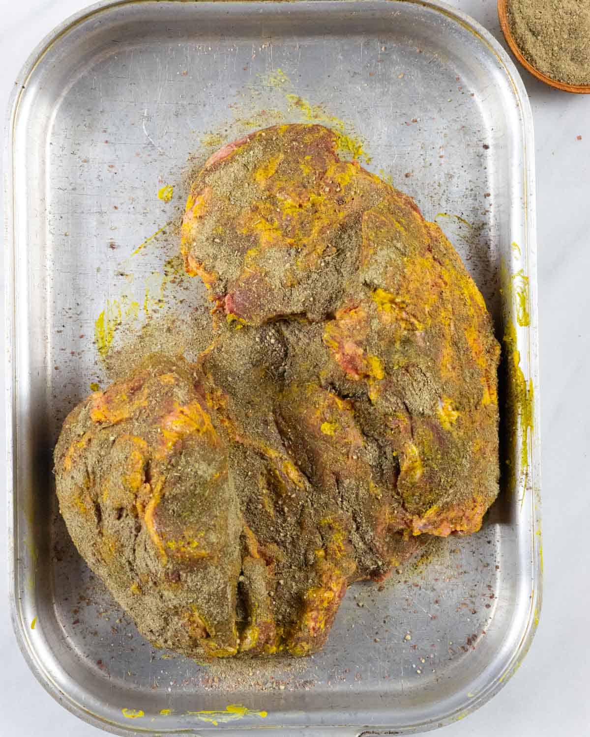 Inside of lamb roast smeared with yellow mustard and sprinkled generously with dry rub mix.