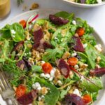Plate of salad with beets, feta and walnuts topped with tahini salad dressing.