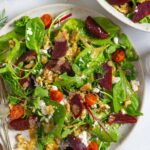 Beet and feta salad on two plates topped with walnuts and tahini dressing.