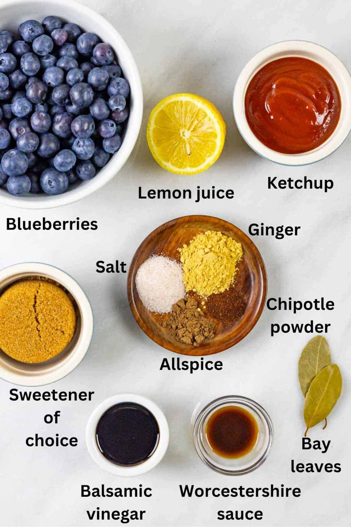Ingredients for blueberry bbq sauce in small bowls on a marble board with black text labels.
