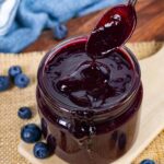 Jar of low-fodmap and low-carb blueberry bbq sauce with a spoon dripping sauce over the jar.