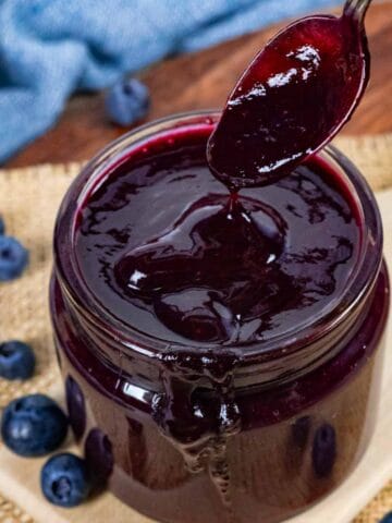 Jar of low-fodmap and low-carb blueberry bbq sauce with a spoon dripping sauce over the jar.