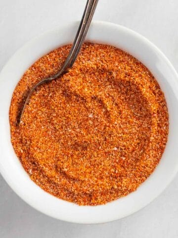 White bowl of buffalo chicken rub seasoning with a spoon in it.