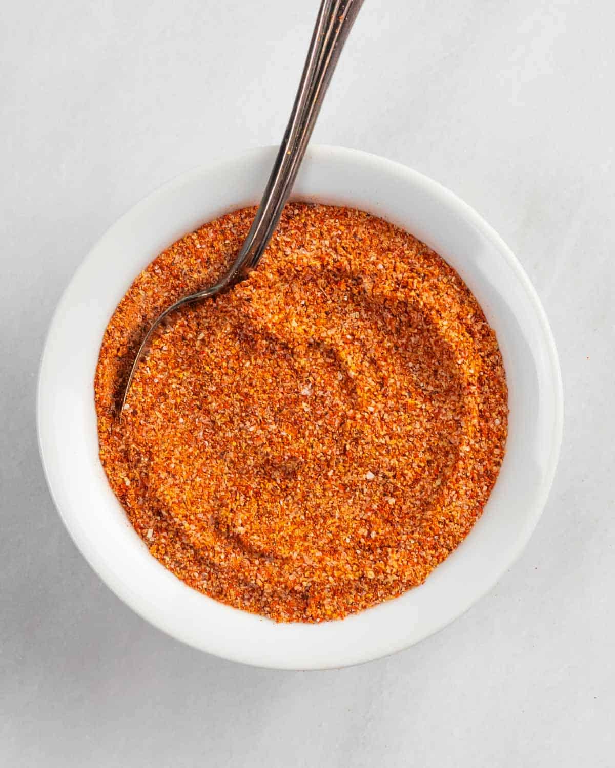Buffalo rub for chicken in a small white bowl with a spoon.