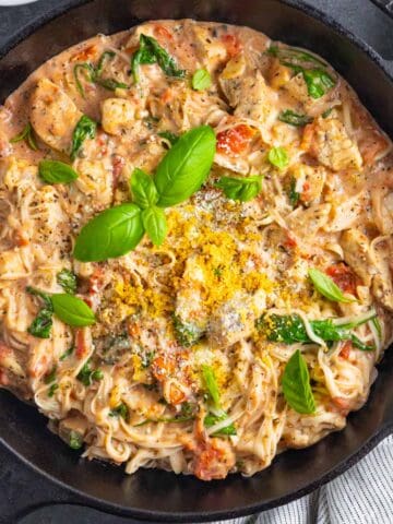Marry me pasta with chicken in a cast iron skillet topped with fresh basil.