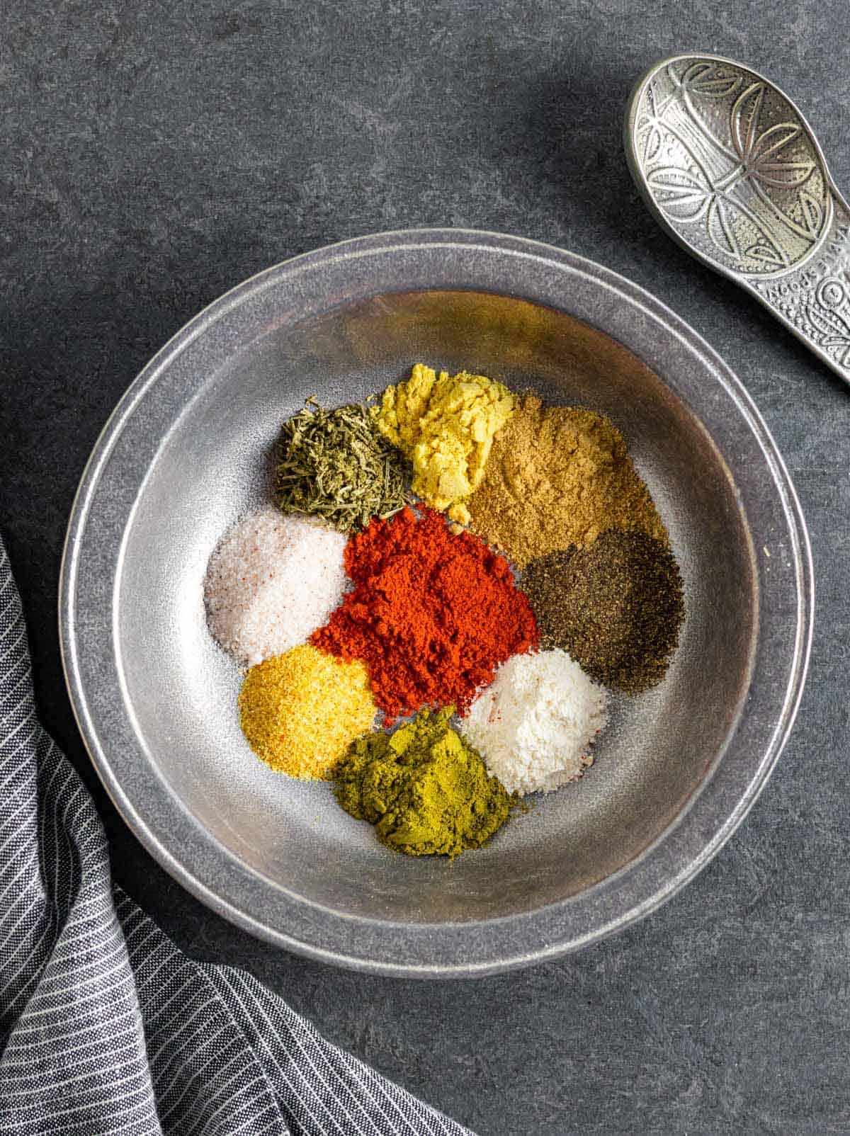 Each colorful ingredient for beef rub in a small pile inside a pewter bowl.