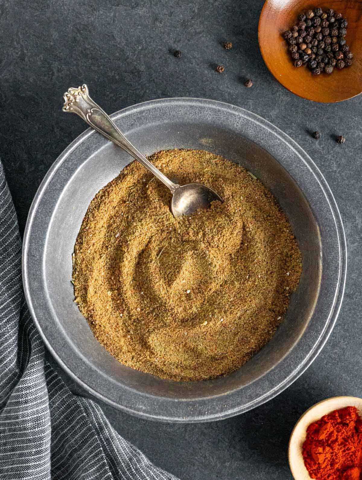 Beef rub seasoning in a pewter bowl with a decorative swirl and spoon.