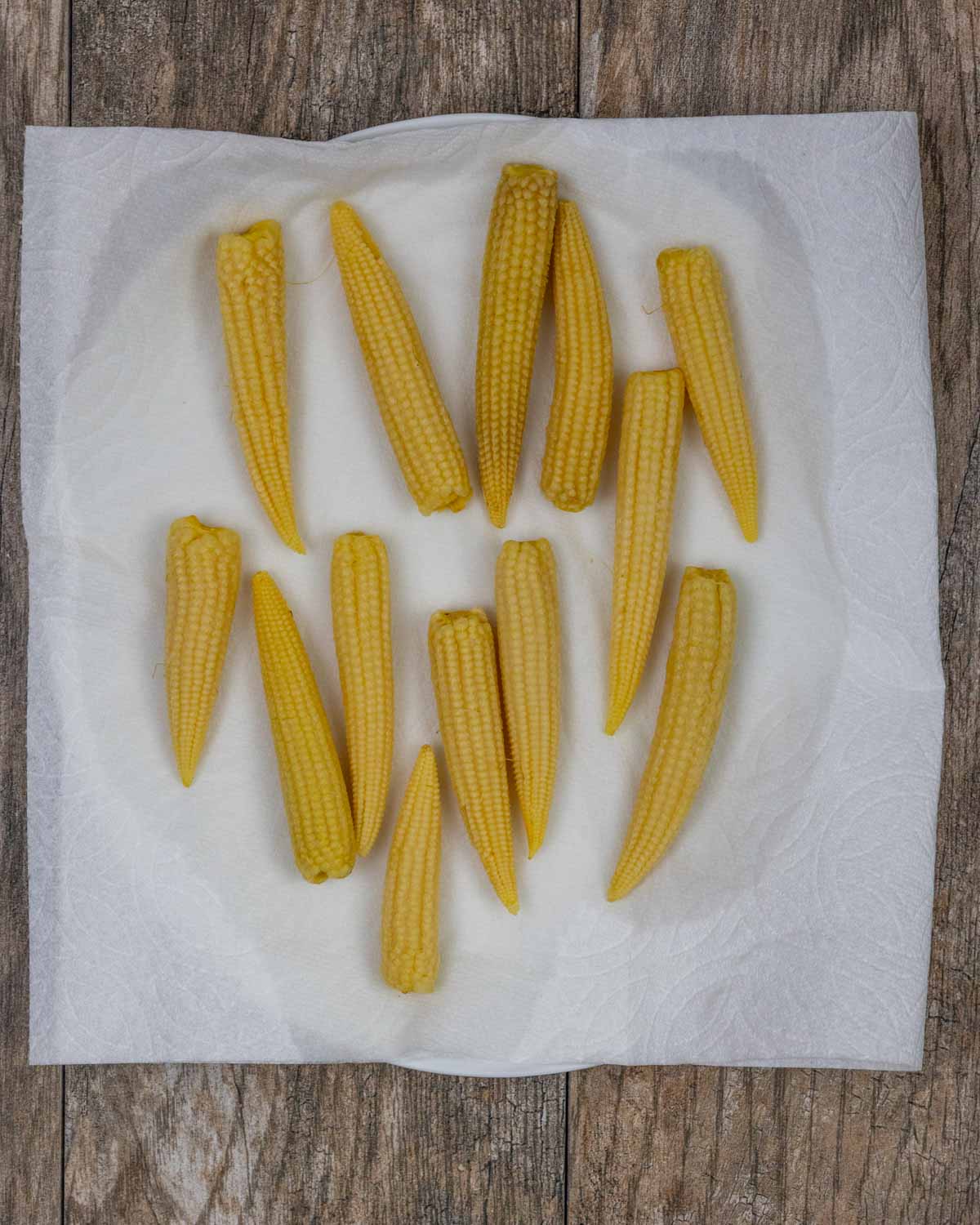 Baby corn on a paper towel on a plate drying.