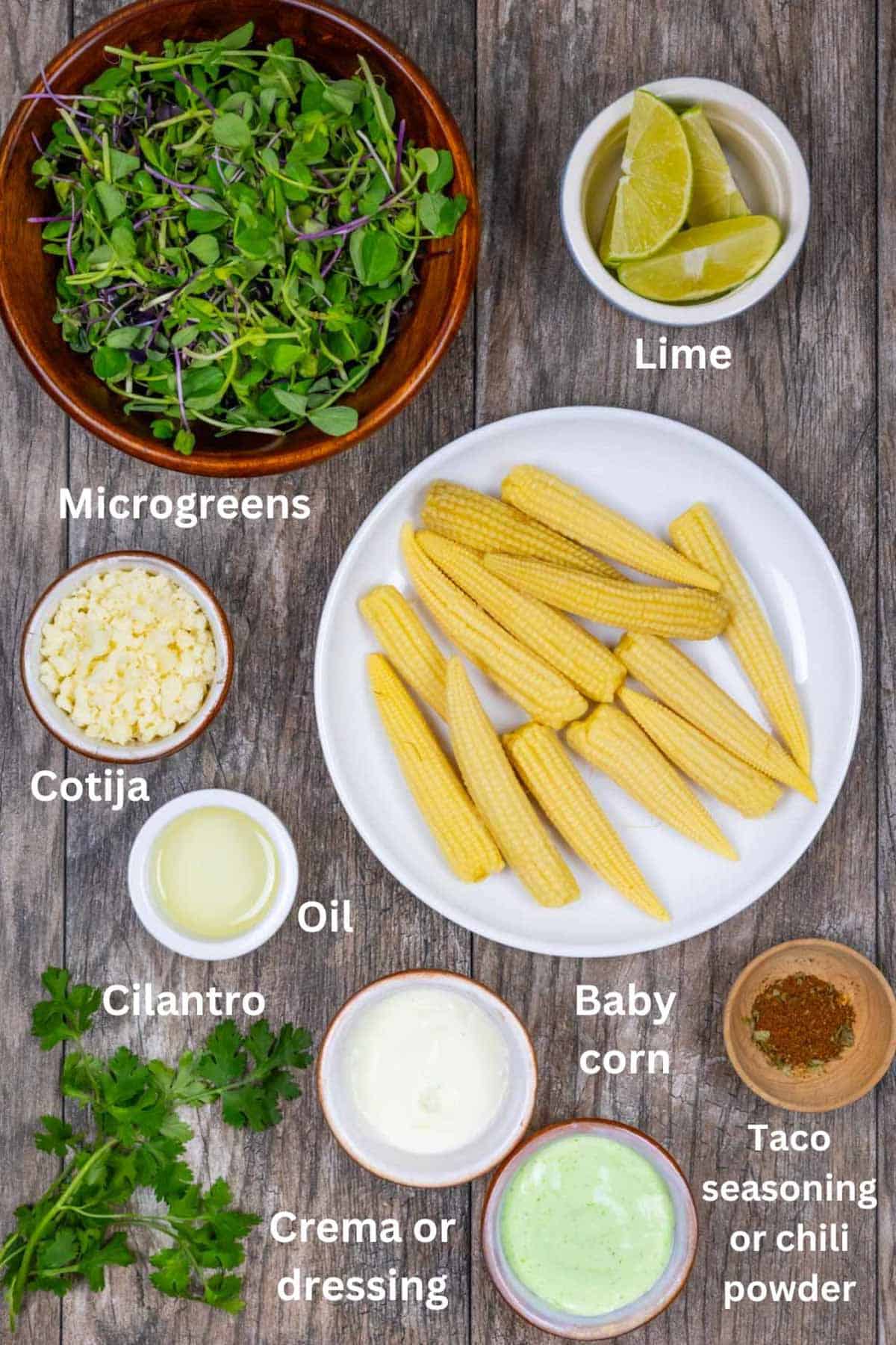 Ingredients for baby corn microgreens salad in small boals on a wood board with white text labels.