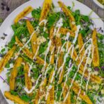 Microgreens salad on a white plate with roasted baby corn and topped with crema dressing.