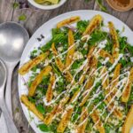 Plate of microgreen salad with roasted baby corn on a wood board with lime garnish.