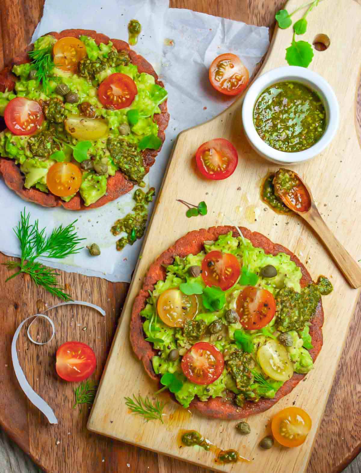 Avocado toast on a board with sandwich thins and pesto.