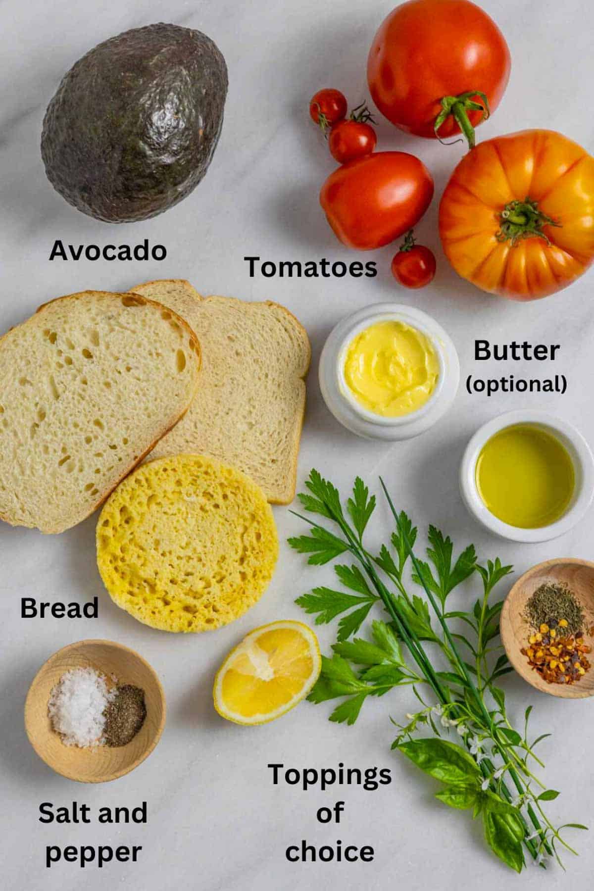 Ingredients for avocado toast laid out on a marble board with black text labels.