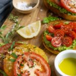 Avocado toast with tomatoes on buttered toast seasoned with salt, pepper and herbs.