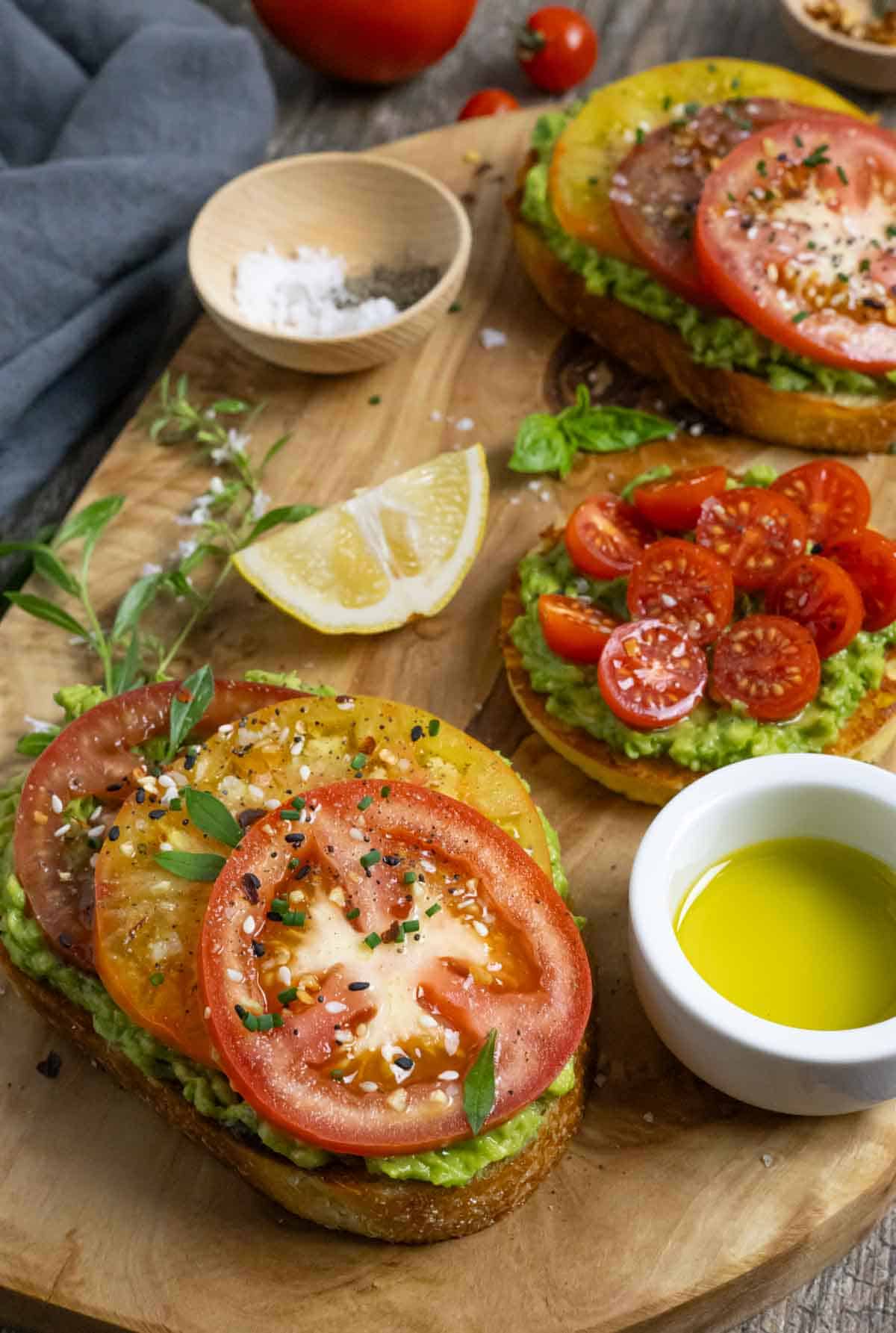 Avocado toast with tomatoes on buttered toast seasoned with salt, pepper and herbs.