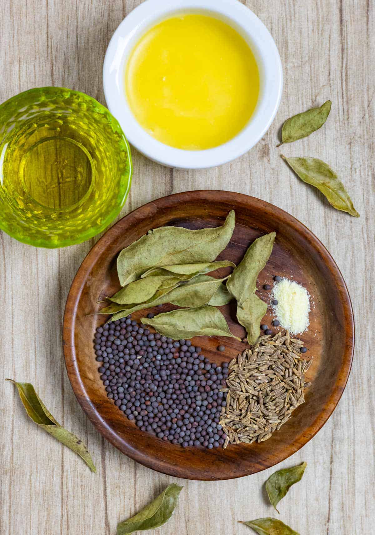 Ingredients for tempering whole herbs on a small wooden plate and in ramekins.