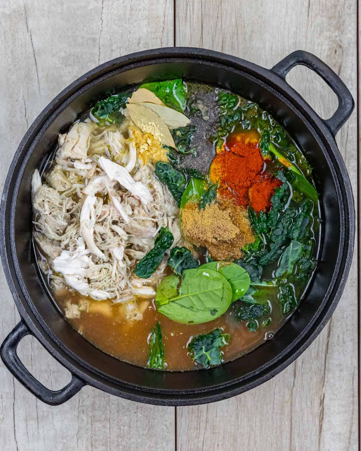 Cast iron dutch oven with turkey lentil soup ingredient added and ready to simmer.