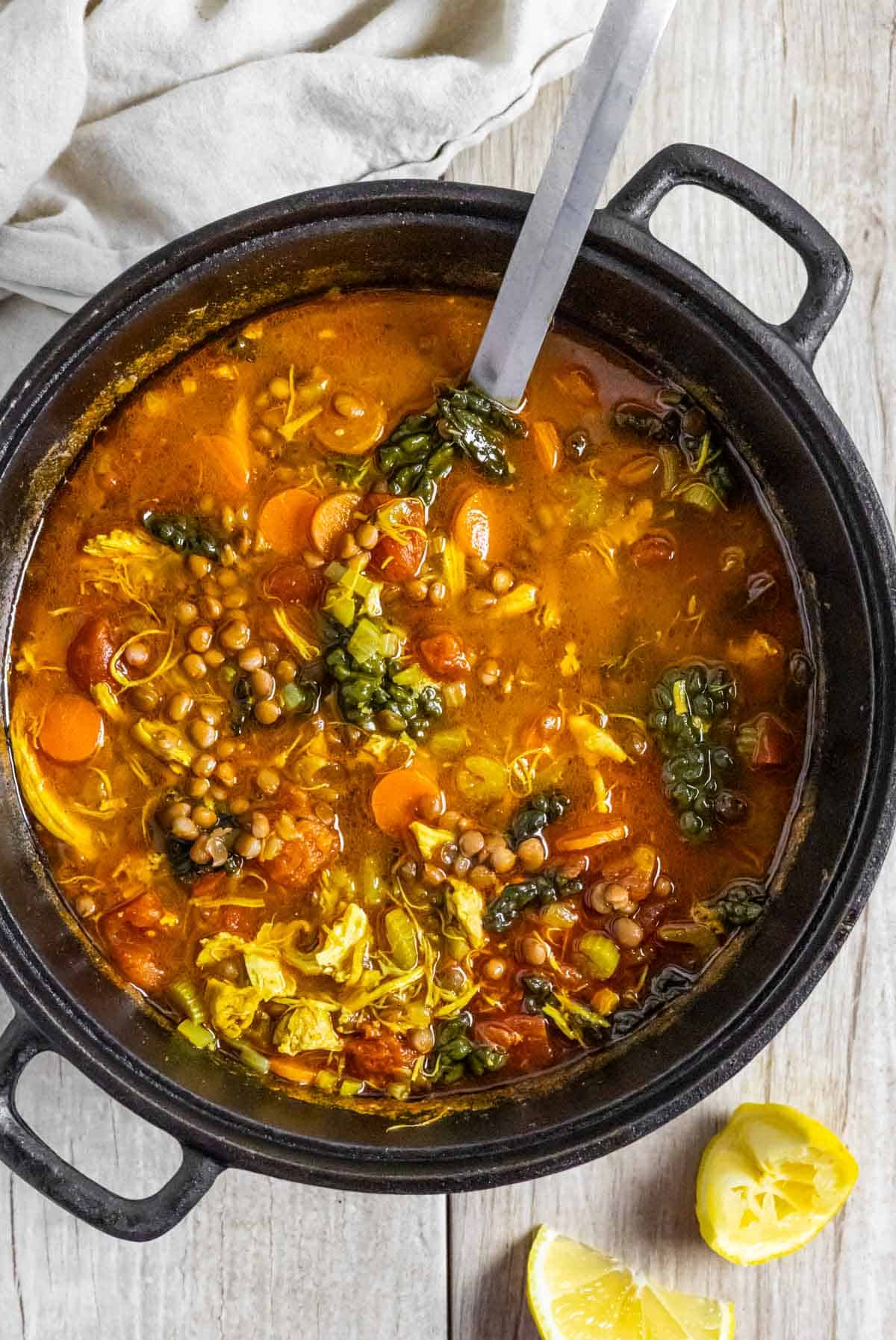 Turkey soup with lentils in a cast iron dutch oven with a serving spoon in the pot.