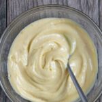 Homemade miso mayonnaise in a glass bowl with a spoon in it.