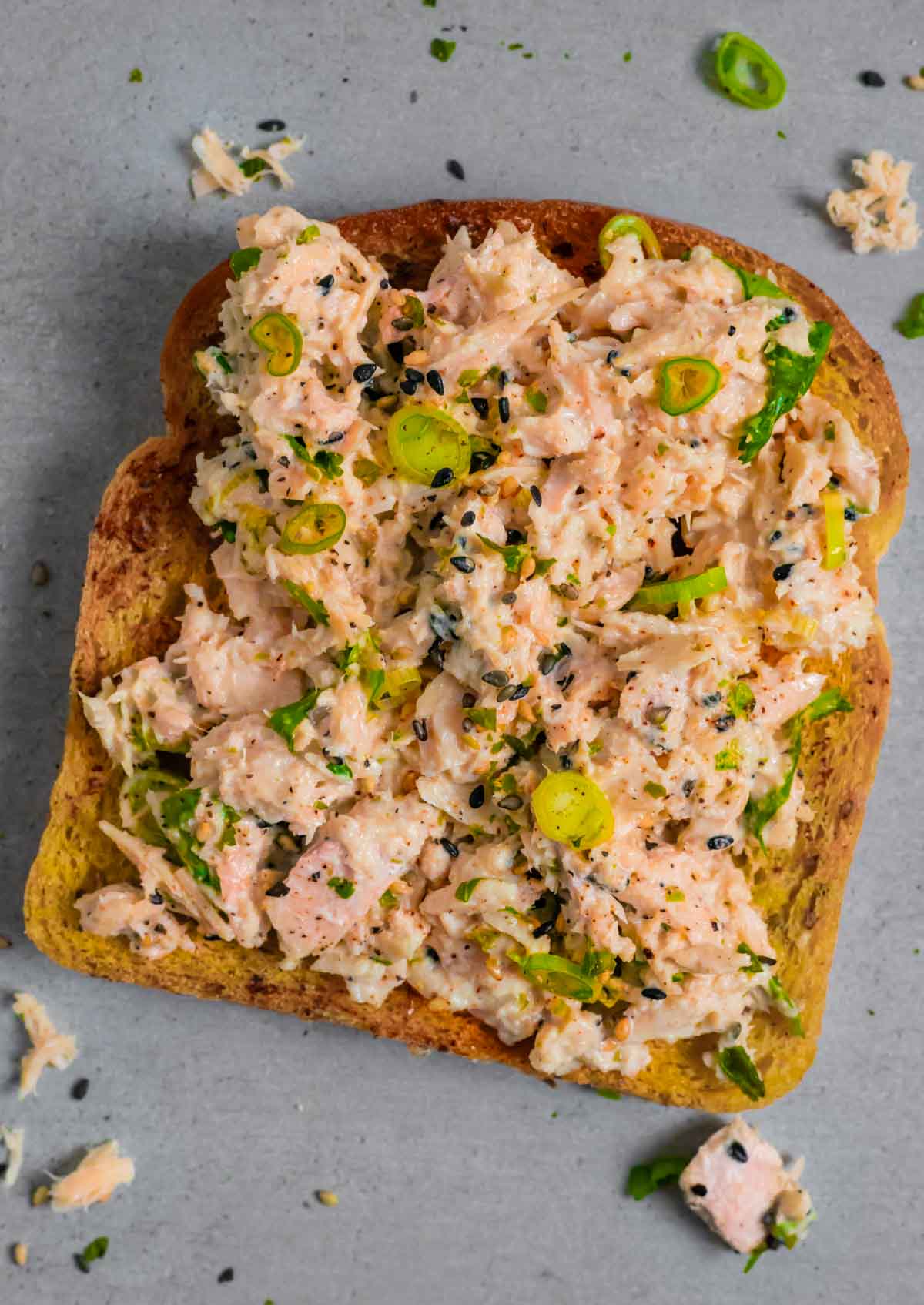 Miso tuna salad open faced on toast on a grey board.