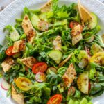 Fattoush salad on a white plate topped with sumac dressing.